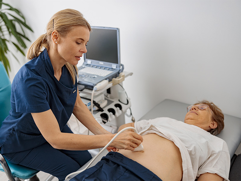 Arzt untersucht bei einem älteren Patienten den Bauchraum mit einem Ultraschallgerät während einer medizinischen Untersuchung.